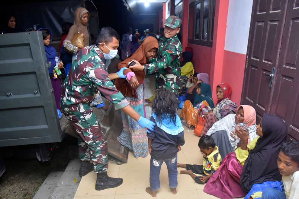 Indonesian soldiers help ethnic Rohingya women and children out of a military truck as they arrive at a temporary shelter in Pidie, Aceh province (Rahmat Mirza/AP)