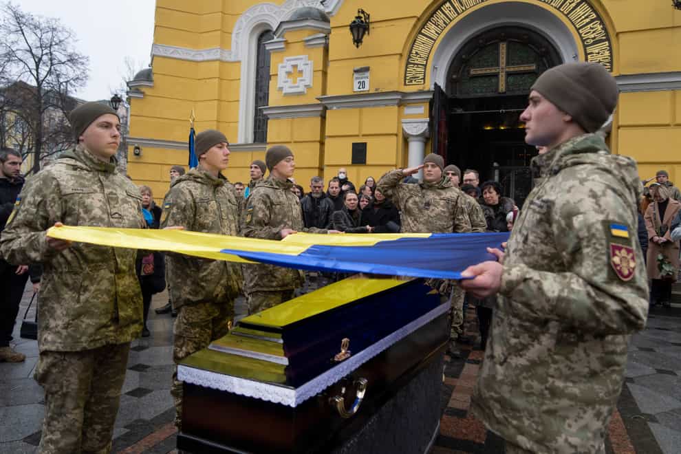 Ukrainian servicemen hold a flag over the coffin of a comrade during a funeral ceremony in Kyiv (Efrem Lukatsky/AP)