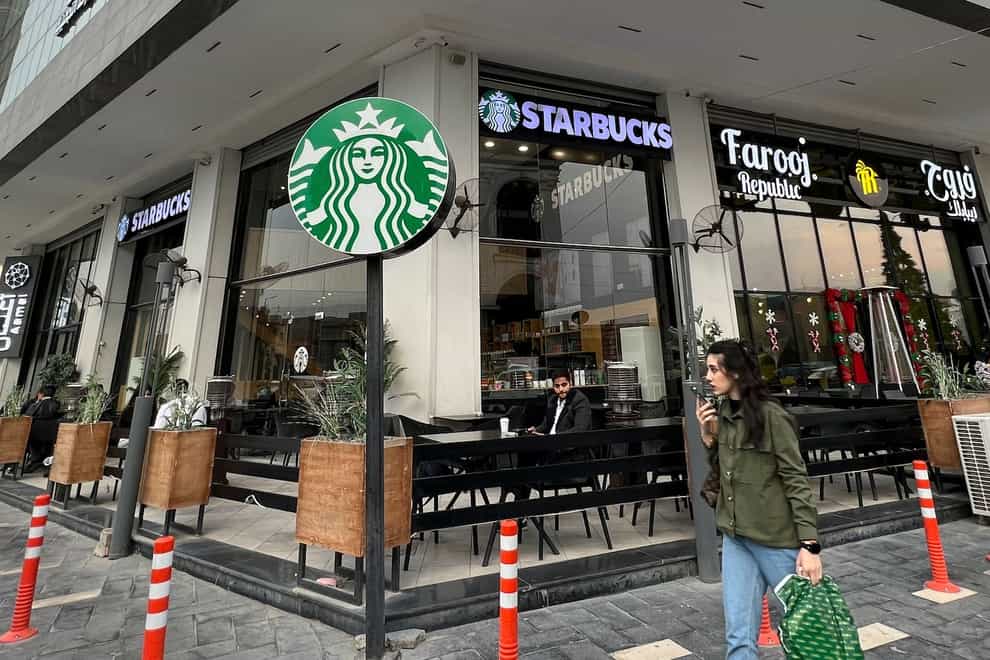 A woman walks by an unlicensed Starbucks cafe in Baghdad (Ali Abdul Hassan/AP)