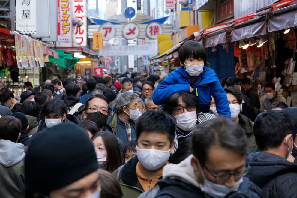 People wearing face masks flock to a shopping street famous for a year-end shopping before New Year holidays in Tokyo, Friday, Dec. 30, 2022. Japan on Friday started requiring Covid-19 tests for all passengers arriving from China (Hiro Komae/AP/PA)