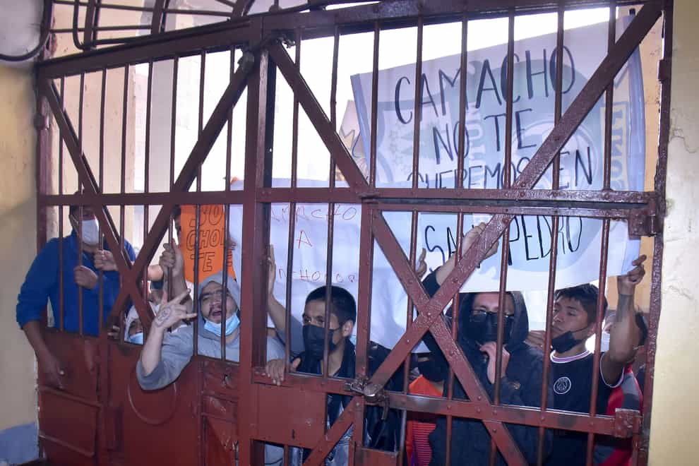 Inmates hold a sign with a message that reads in Spanish: “Camacho, we do not want you here in San Pedro”, during a protest against the possible transfer of Santa Cruz Gov. Luis Fernando Camacho to the detention facility in La Paz, Bolivia (Jose Lavayen/AP/PA)