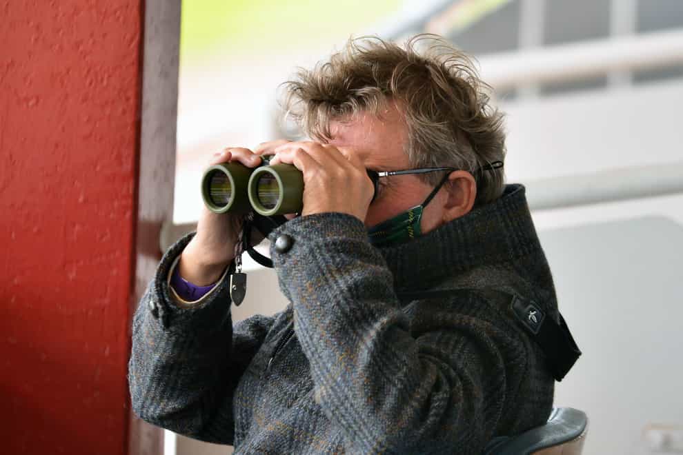 Trainer Mark Johnston watching through binoculars at Redcar Racecourse.