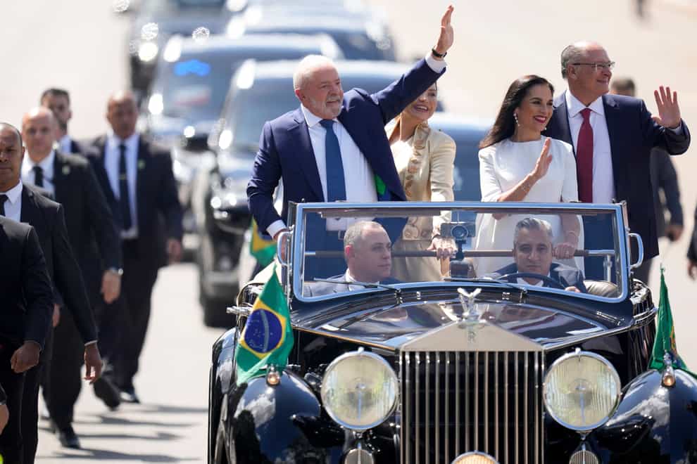 President-elect Luiz Inacio Lula da Silva, left, his wife Rosangela Silva, second from left, vice president-elect Geraldo Alckmin, right, and his wife Maria Lucia Ribeiro ride in an open car to congress for their swearing-in ceremony in Brasilia, Brazil (Andre Penner/AP)