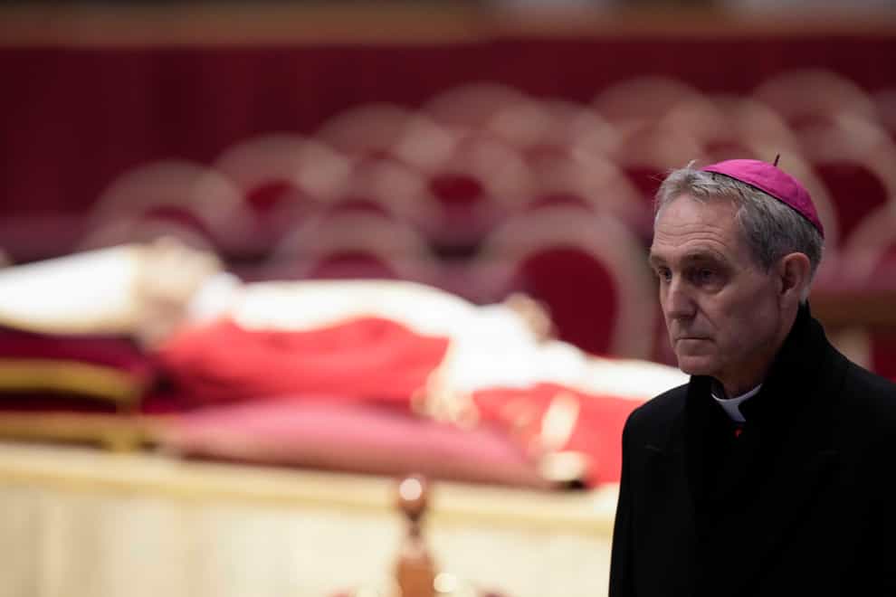 The body of late Pope Emeritus Benedict XVI is laid out in state as Father Georg Gaenswein stands nearby (Andrew Medichini/AP/PA)