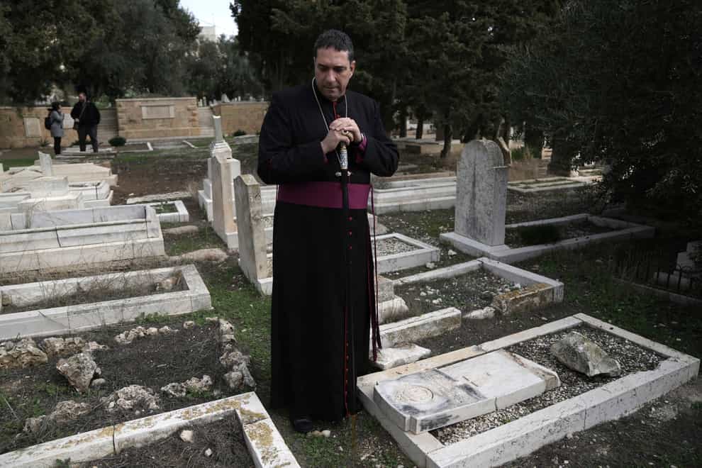 Hosam Naoum, a Palestinian Anglican bishop, pauses where vandals desecrated more than 30 graves (Mahmoud Illean/AP)