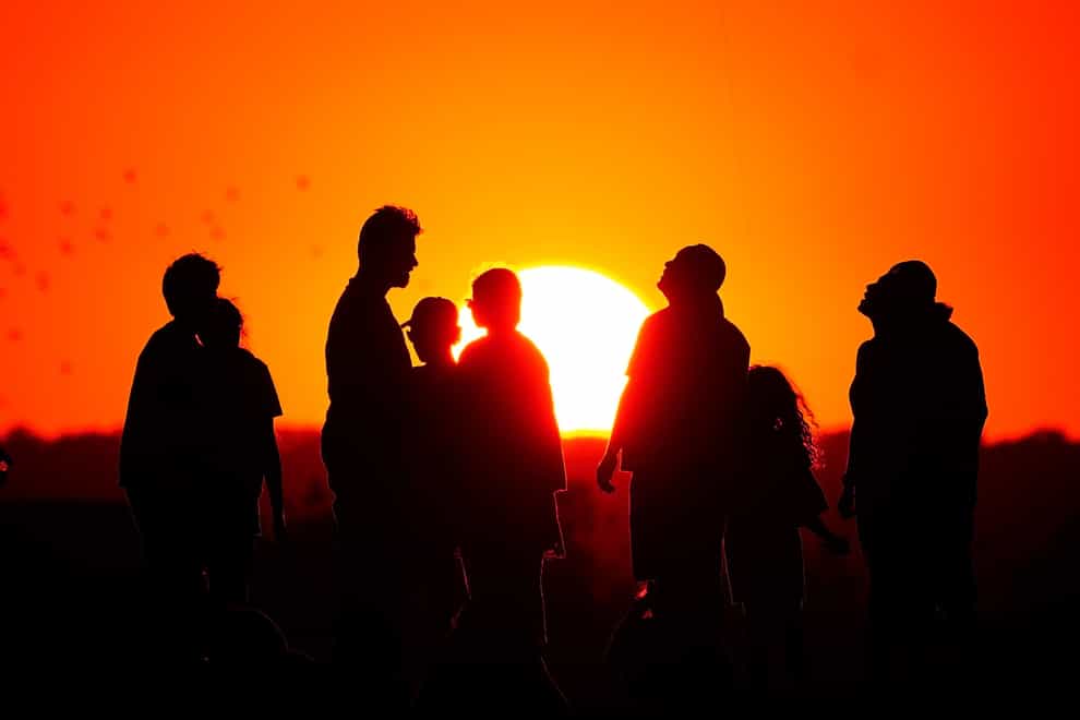 A crowd of people watch the setting sun from a hill in Ealing, west London (Victoria Jones/PA)
