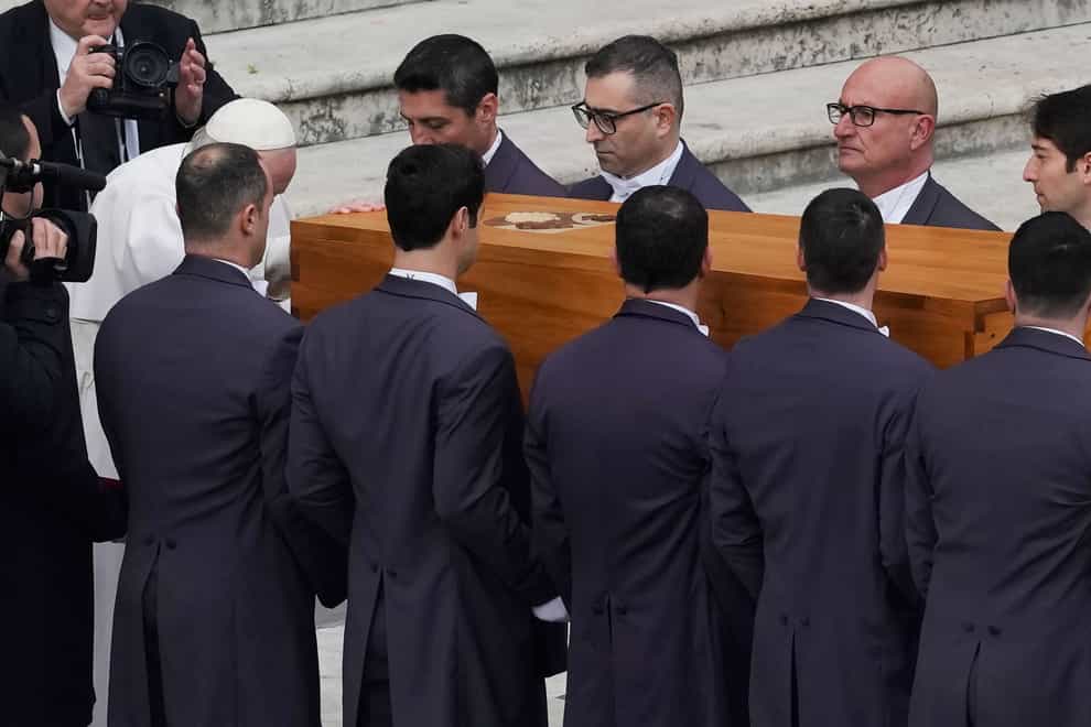 Pope Francis touches the coffin of late Pope Emeritus Benedict XVI after a funeral mass in St Peter’s Square at the Vatican (Antonio Calanni/AP)