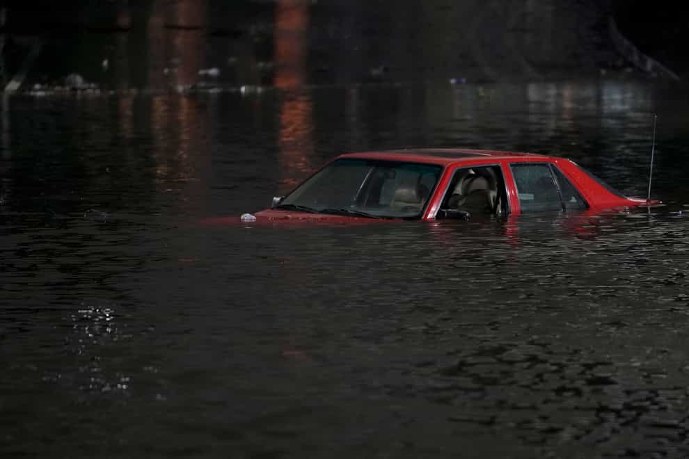 An empty vehicle is surrounded by floodwaters on a road in Oakland, California (Godofredo A Vasquez/AP)