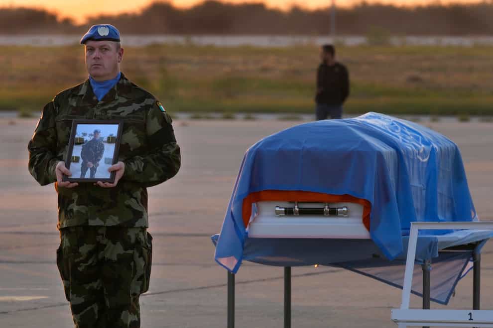An Irish UN peacekeeper stands next to the coffin draped by the United Nations flag of his comrade Private Sean Rooney who was killed during a confrontation with residents near the southern town of Al-Aqbiya (Hussein Malla/AP)