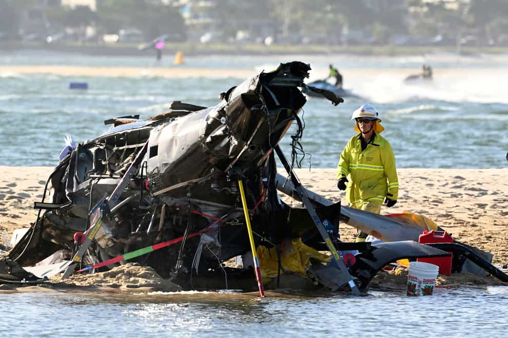 An emergency worker looks over a crashed helicopter following a collision near SeaWorld, on the Gold Coast, Australia (Dave Hunt/AAP Image/AP)
