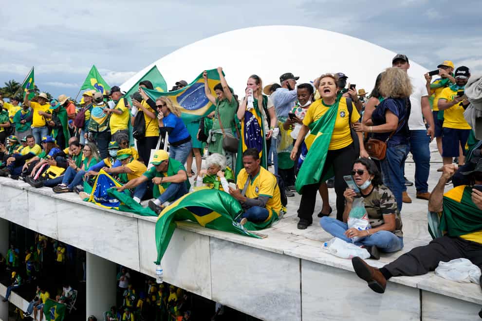 Protesters, supporters of Brazil’s former President Jair Bolsonaro, stand on the roof of the National Congress building (AP)