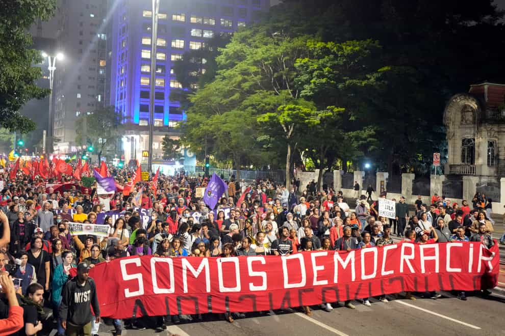 Demonstrators march holding a banner that reads in Portuguese ‘We are Democracy’ (Andre Penner/AP)
