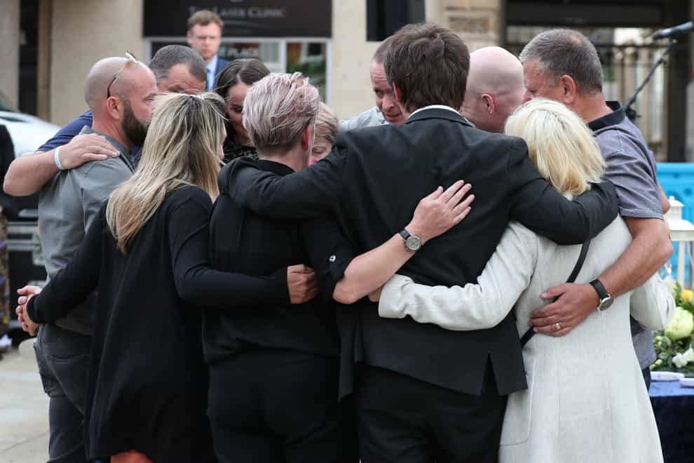Family members of the three victims comfort each other after lighting candles during a vigil at Market Place, Reading, in memory of David Wails, Joseph Ritchie-Bennett and James Furlong, who were killed in the Reading terror attack in Forbury Gardens in the town centre, shortly before 7pm on June 20 (Steve Parsons/PA)