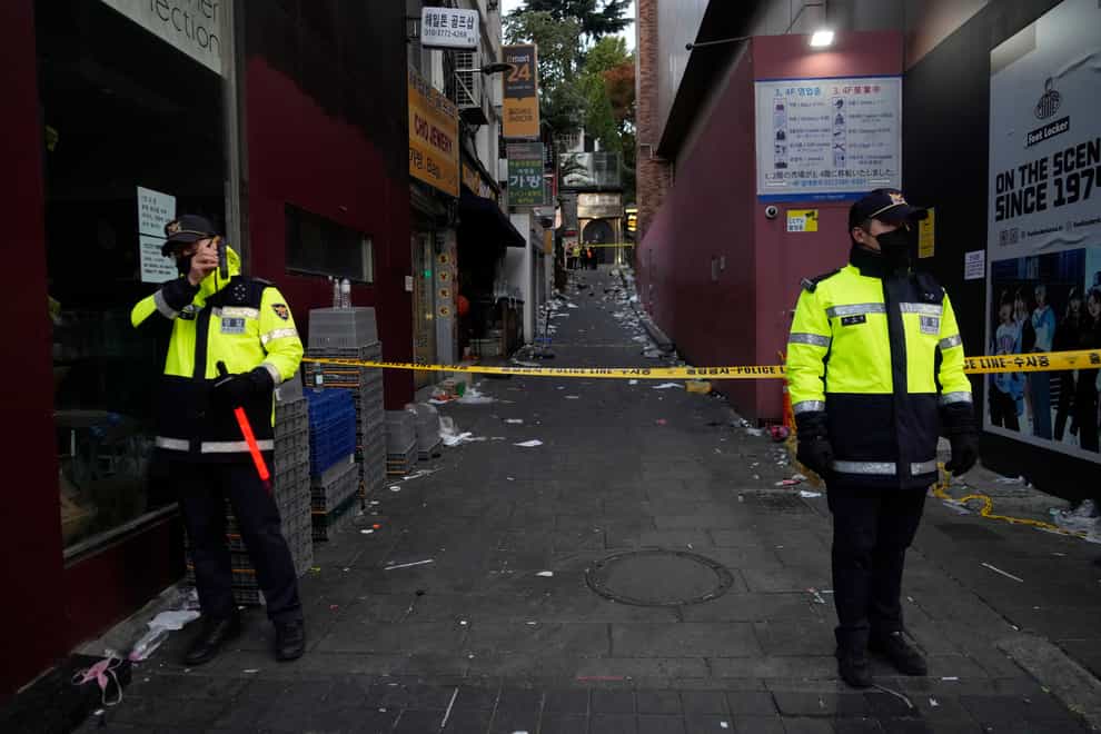 Police officers stand guard at the scene where dozens of people died and were injured during a crowd surge in Seoul, South Korea (Ahn Young-joon/AP)