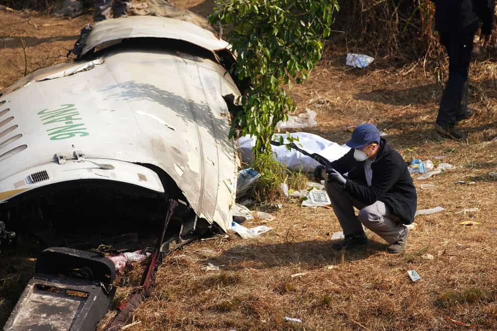 A French investigator takes a photo of the wreckage of a passenger plane at the crash site, in Pokhara, Nepal (Yunish Gurung/AP)
