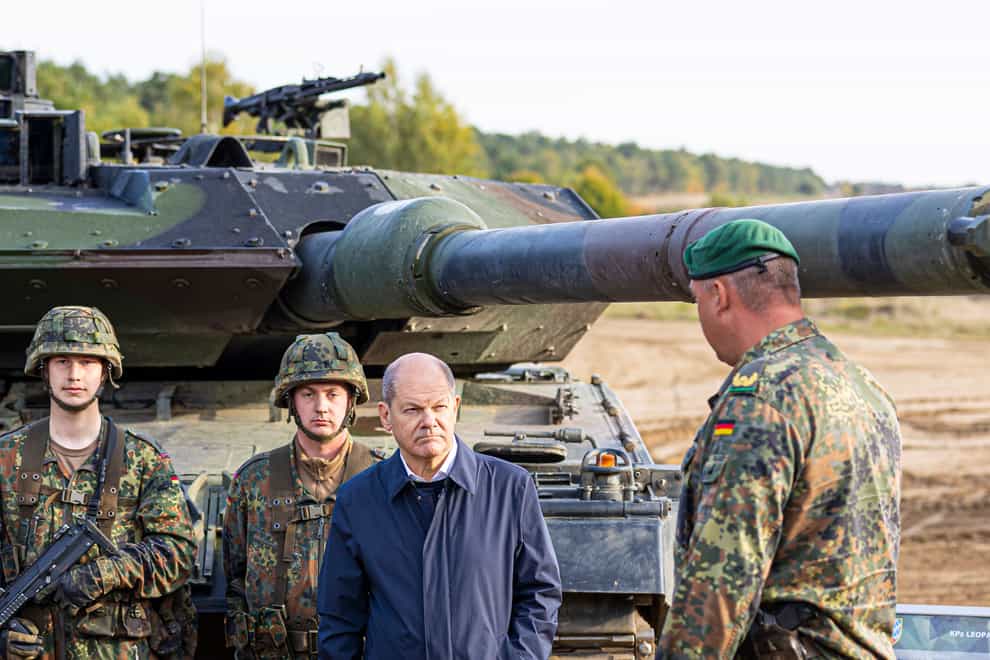 German Chancellor Olaf Scholz stands with German soldiers beside a Leopard 2 main battle tank during a training exercise in Ostenholz in October (Moritz Frankenberg/dpa/AP)