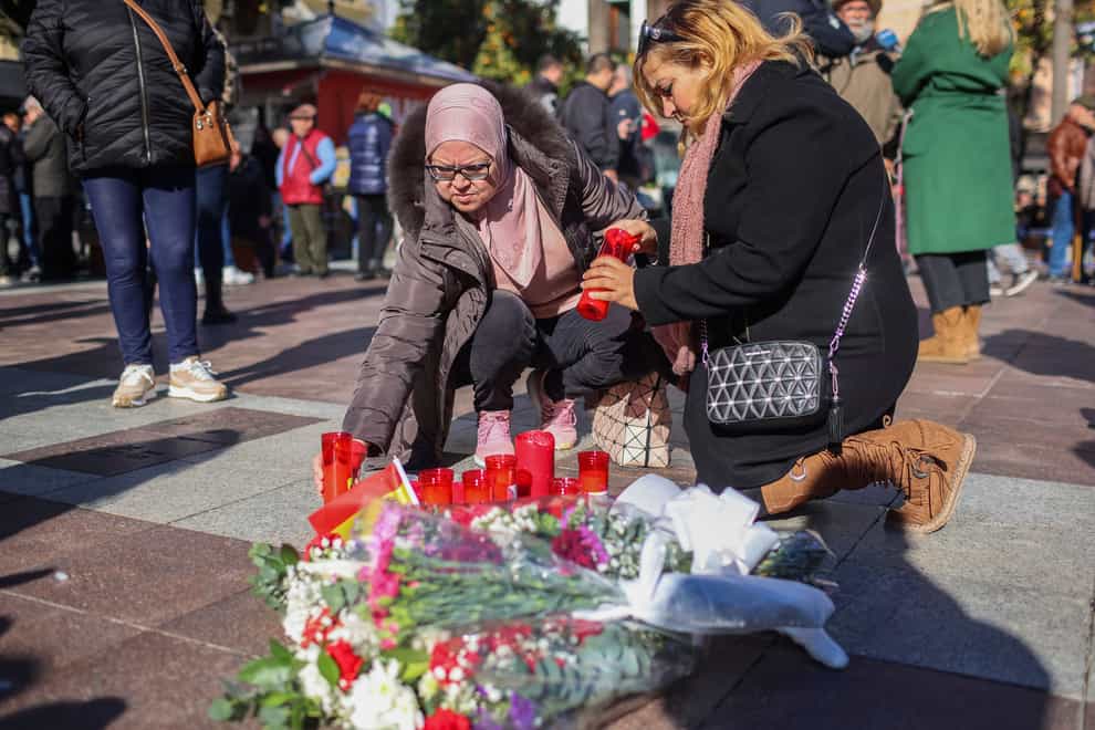 Two women light candles in memory of a church sacristan killed on Wednesday in Algeciras, southern Spain (Juan Carlos Toro/AP)
