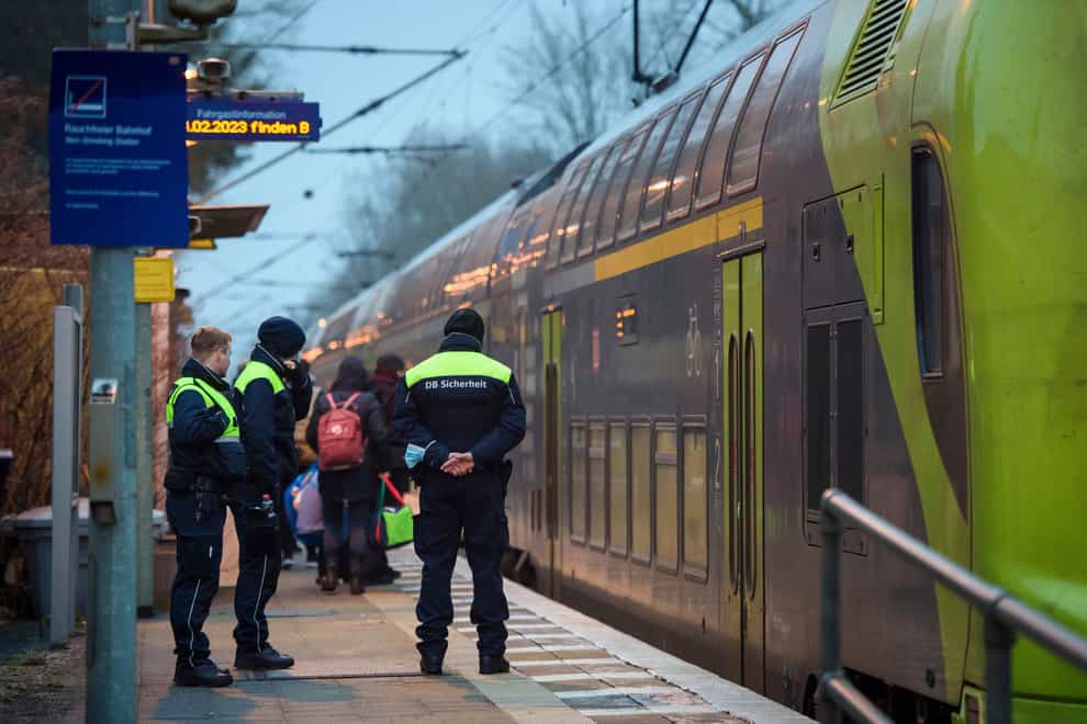 Deutsche Bahn security guards stand on the platform at Brokstedt station at dawn in Brokstedt, Germany (Gregor Fischer/dpa/AP)