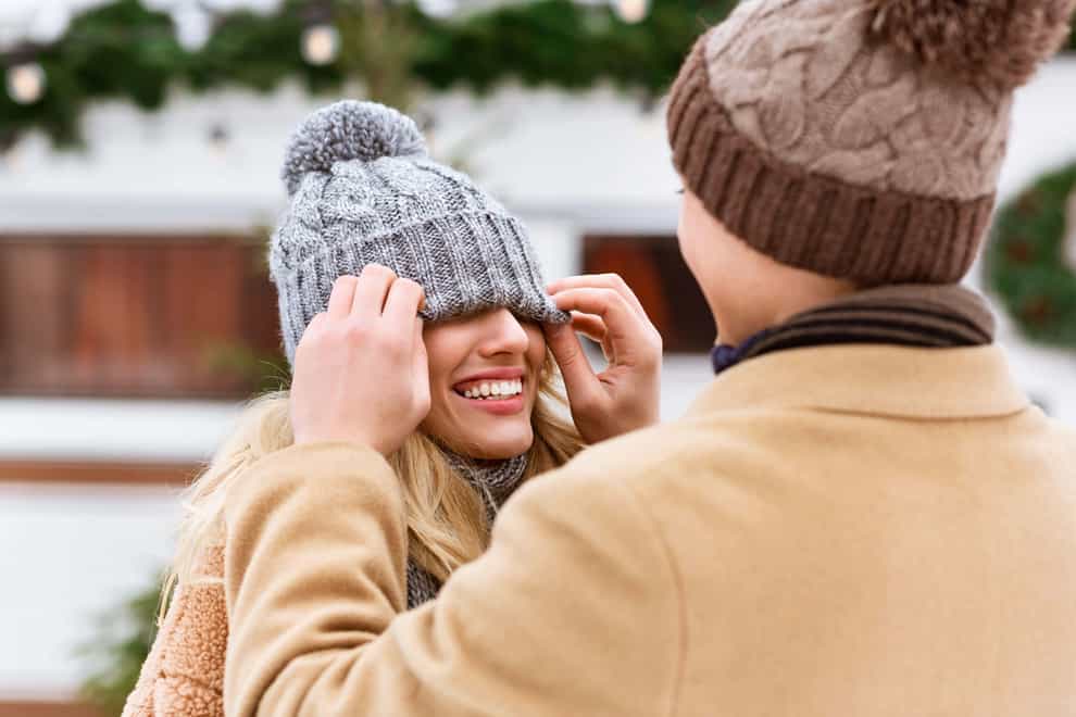 2CFY8D7 Romantic couple having fun outdoors in winter, man playing with girlfriend’s hat
