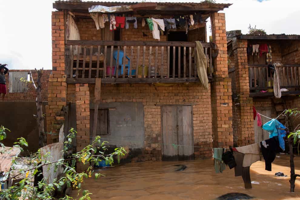 A young boy stands on the upper floor of a house overlooking a flooded residential street in Madagascar (Alexander Joe/AP)