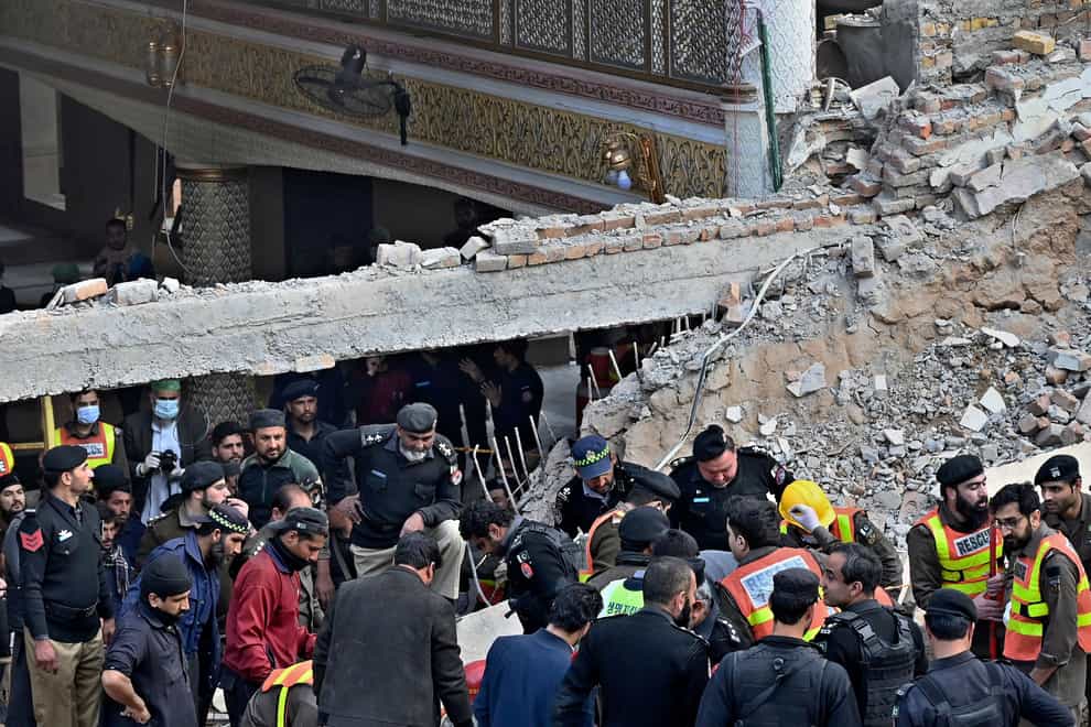 Security officials and rescue workers search for survivors at the site of the suicide bombing (Zubair Khan/AP)