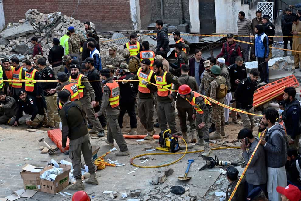 Security officials and rescue workers gather at the site of suicide bombing, in Peshawar, Pakistan (Zubair Khan/AP)