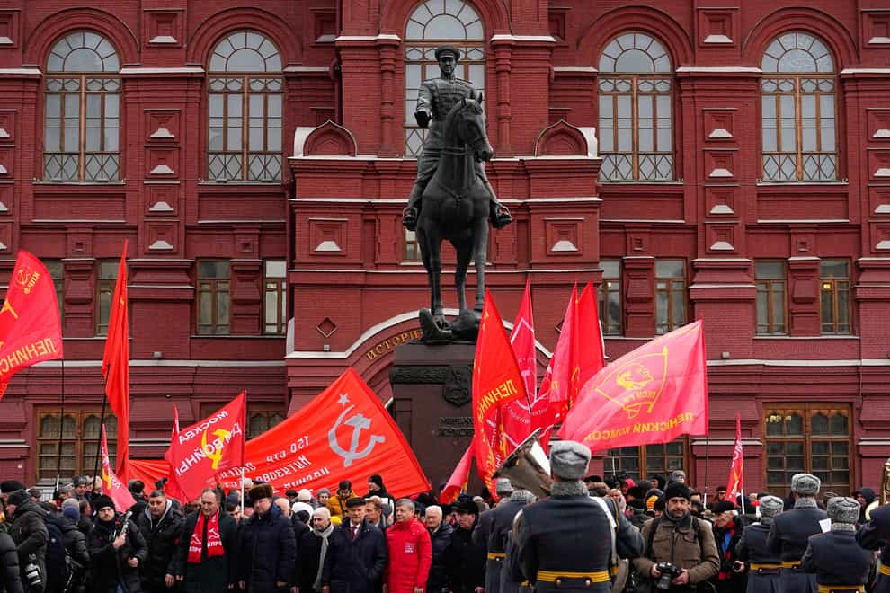 Communist party supporters with red flags gather around the statue of Soviet Marshal Georgy Zhukov after a wreath-laying ceremony at the Tomb of the Unknown Soldier near the Kremlin Wall (Alexander Zemlianichenko/AP)
