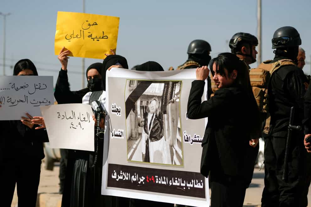 Demonstrators hold placards and a poster with a picture of Tiba Ali, a YouTube star who was recently killed by her father, in Diwaniya, Iraq (Hadi Mizban/AP)