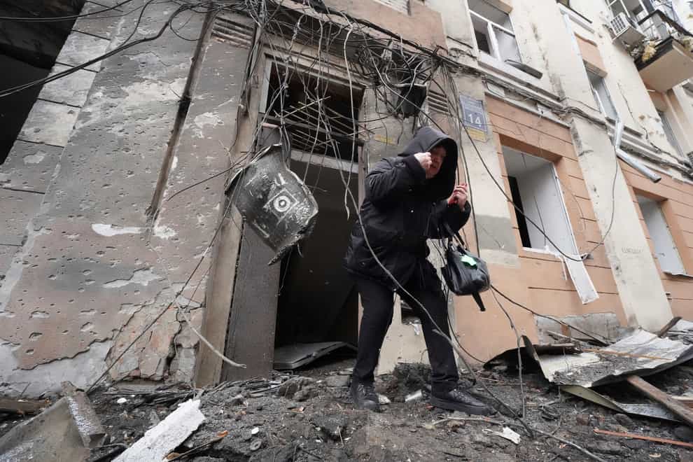 A woman walks out from a residential building which was hit by a Russian rocket, in the city centre of Kharkiv (AP)