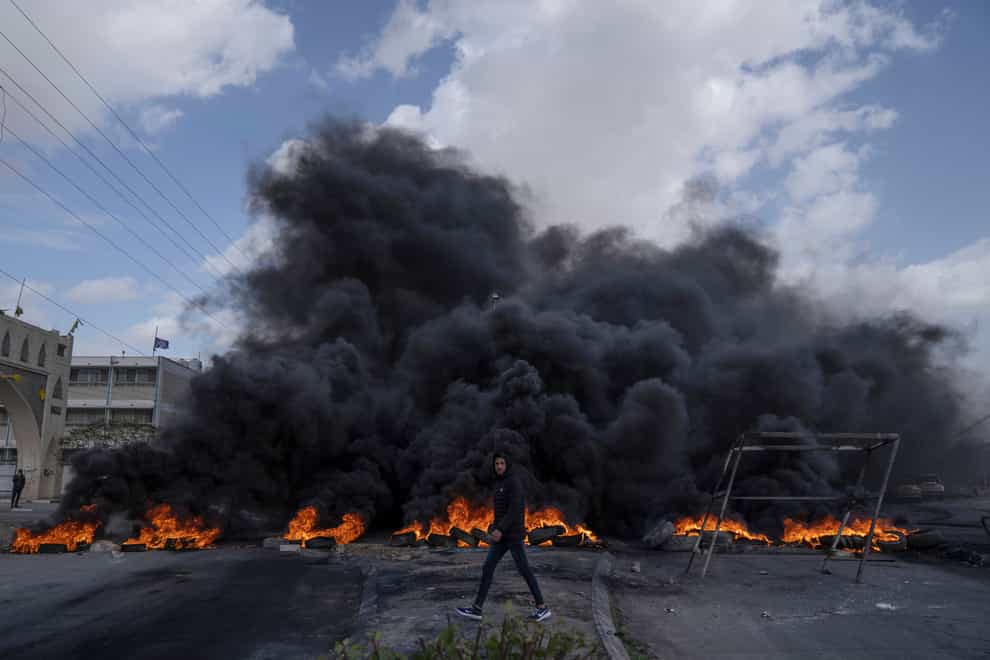 Palestinian protesters block the main road with burning tires in the West Bank city of Jericho (AP)