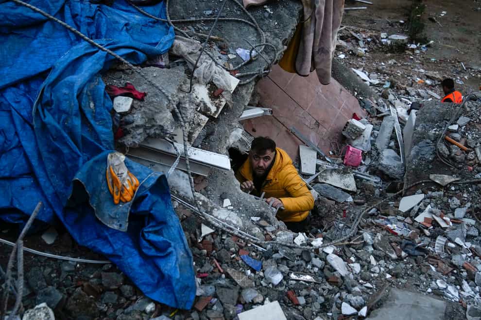 A man searches for people in a destroyed building in Adana, Turkey (Khalil Hamra/AP)