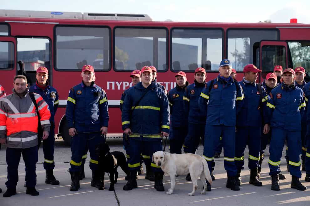 Greek firefighters with dogs wait to board a military plane at Elefsina Air Force Base, in western Athens, Greece (Thanassis Stavrakis/PA)
