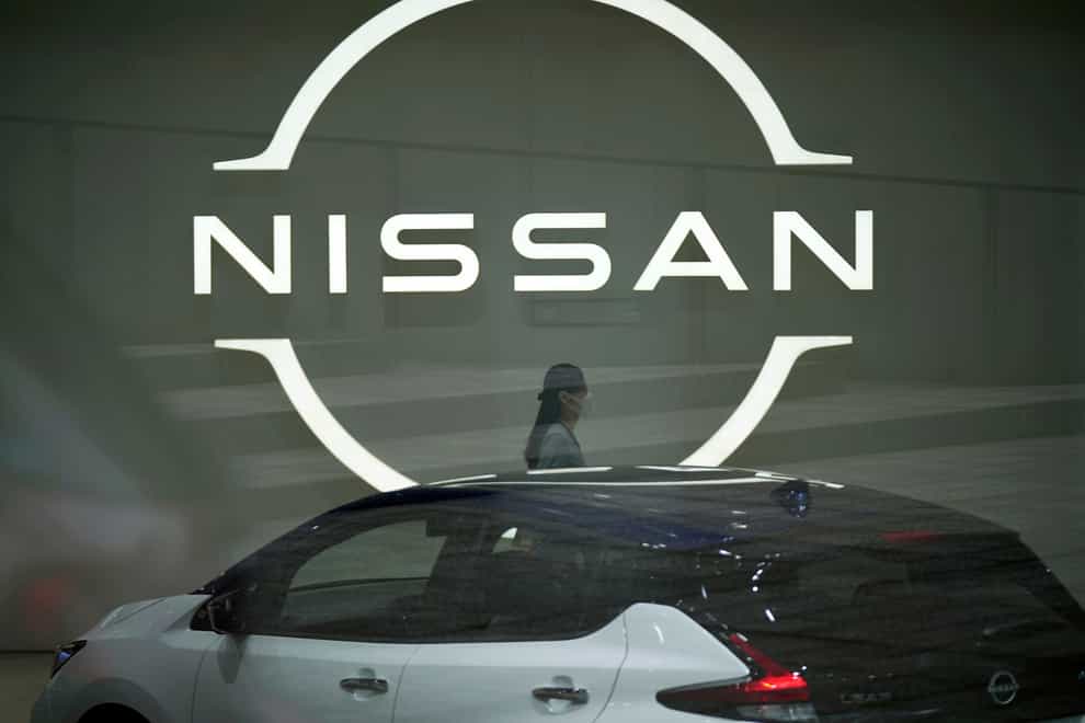 A worker walking near a Nissan logo at Nissan’s headquarters (Eugene Hoshiko/AP)