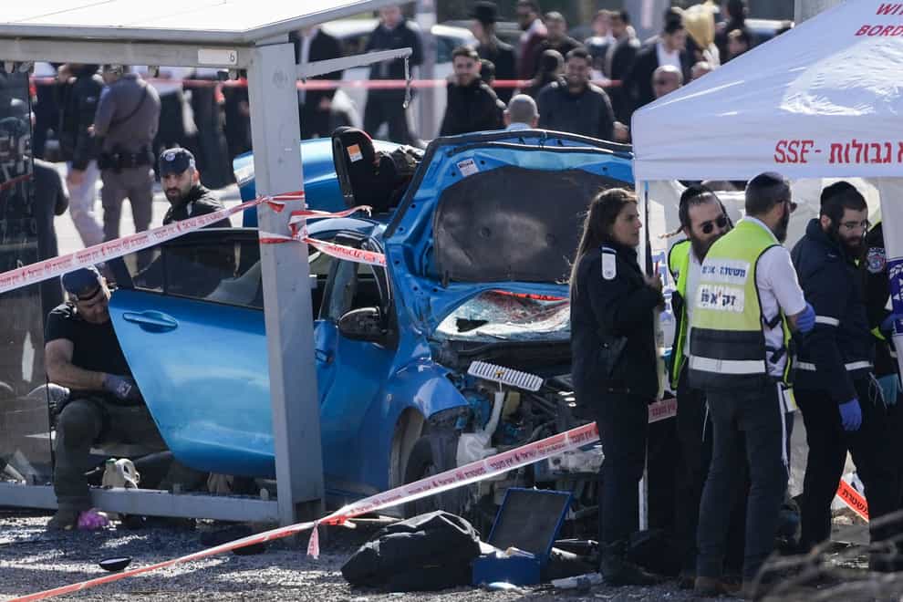 Members of Zaka Rescue and Recovery team and Israeli police forensic team work at the site of a car-ramming attack at a bus stop in Ramot (AP)