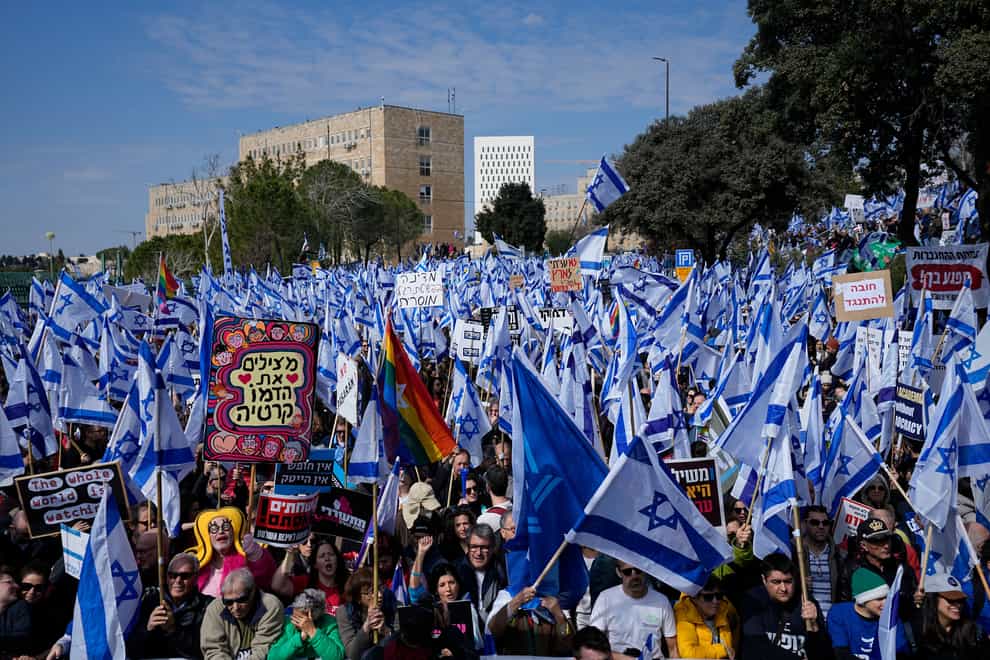 Israelis wave national flags during a protest outside the Knesset in Jerusalem against plans by Prime Minister Benjamin Netanyahu’s new government to overhaul the judicial system (Ohad Zwigenberg/AP)