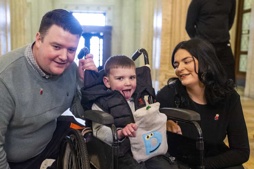 Six-year-old Daithi Mac Gabhann with his parents, father Mairtin Mac Gabhann (left) and mother Seph Ni Mheallain (right), at Parliament Buildings at Stormont (Liam McBurney/PA)