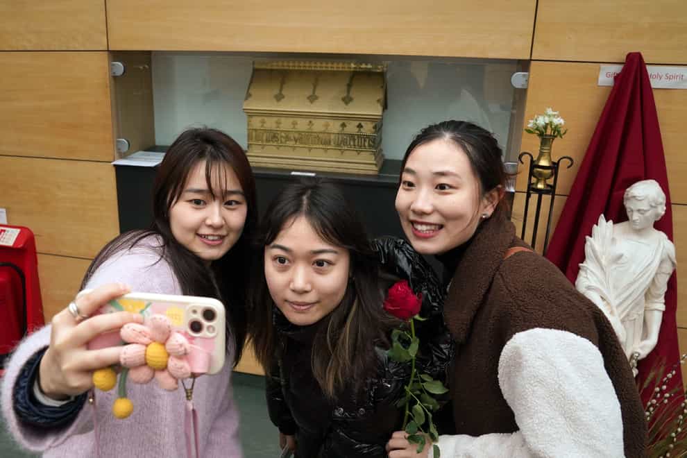 Friends l-r Mila He, Yuki Fan and Nan Chen take a selfie beside a chest containing bones belonging to St Valentine at the Blessed John Duns Scotus church in the Gorbals, Glasgow. (Andrew Milligan/PA)