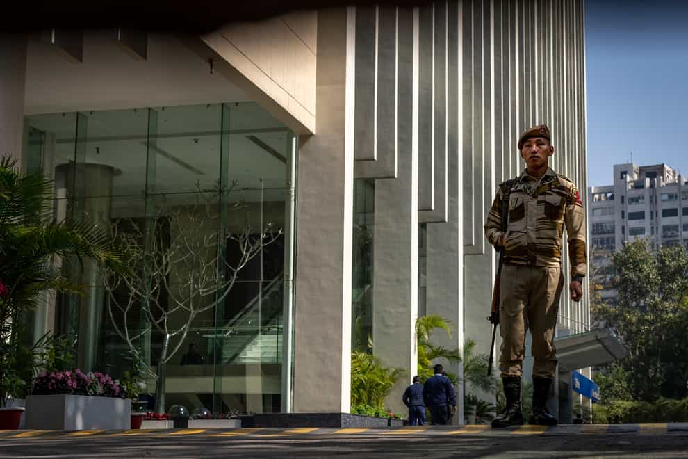 An armed security person stands guard at the gate of a building housing BBC offices in New Delhi, India (Altaf Qadri/AP)