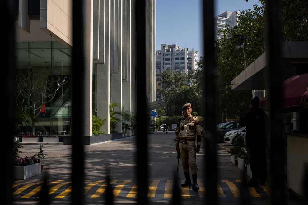 An armed security person stands stand guard at the gate of a building housing BBC office in New Delhi (AP Photo/Altaf Qadri)