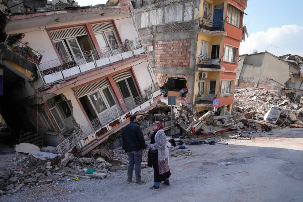 Tw people talk as they stand amidst damaged buildings in Hatay, Turkey, Saturday, Feb. 11, 2023. Emergency crews made a series of dramatic rescues in Turkey on Friday and Saturday, pulling several people from the rubble days after a catastrophic 7.8-magnitude earthquake killed thousands in Turkey and Syria. (AP Photo/Hussein Malla)