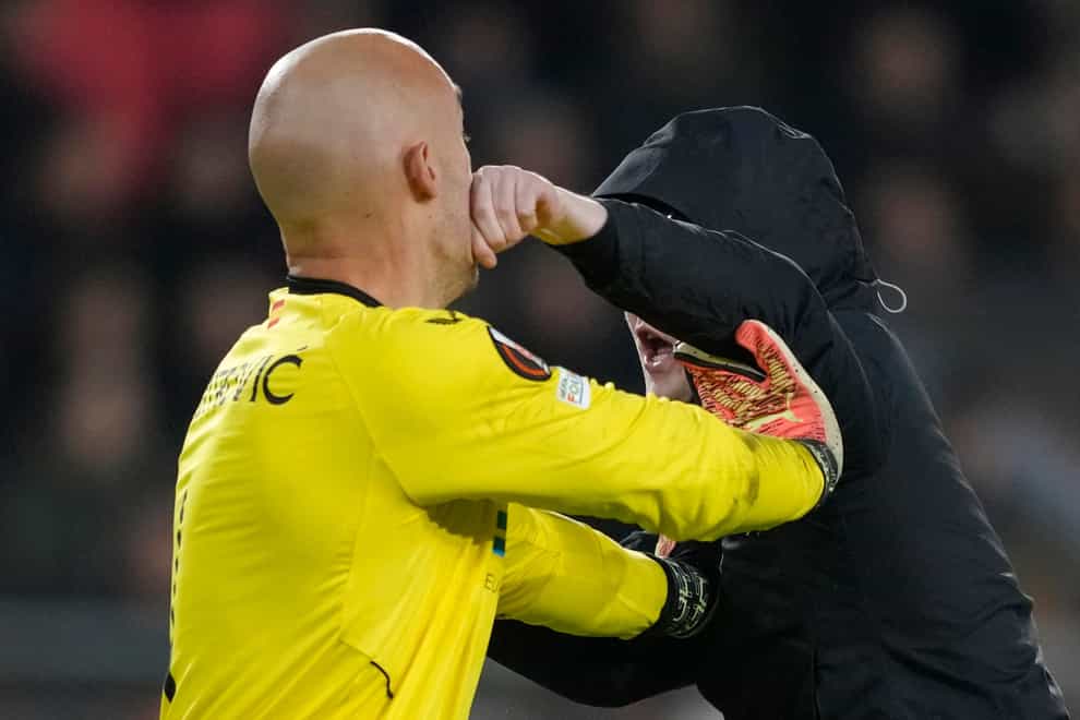 A PSV supporter punches Sevilla’s goalkeeper Marko Dmitrovic in the face (Peter Dejong/AP)