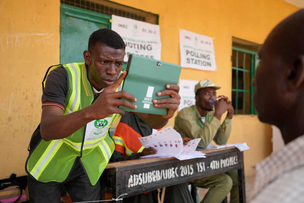 A man has his photo taken by an electoral worker before voting during the presidential elections in Yola, Nigeria (Sunday Alamba/AP)