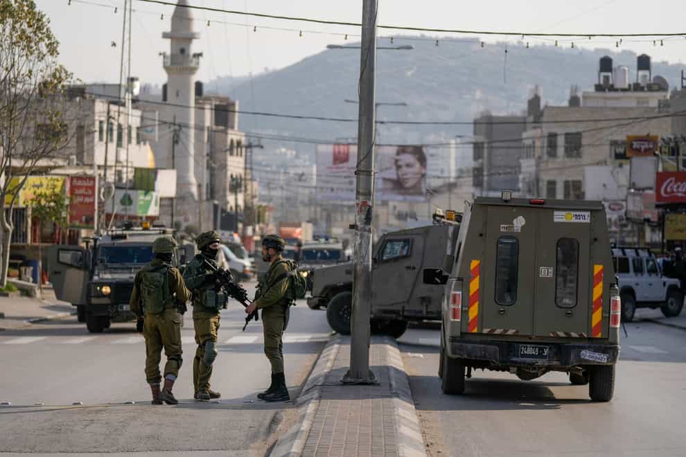 Israeli soldiers take up positions at the scene of a Palestinian shooting attack on an Israeli car at the Hawara checkpoint (Majdi Mohammed/AP)