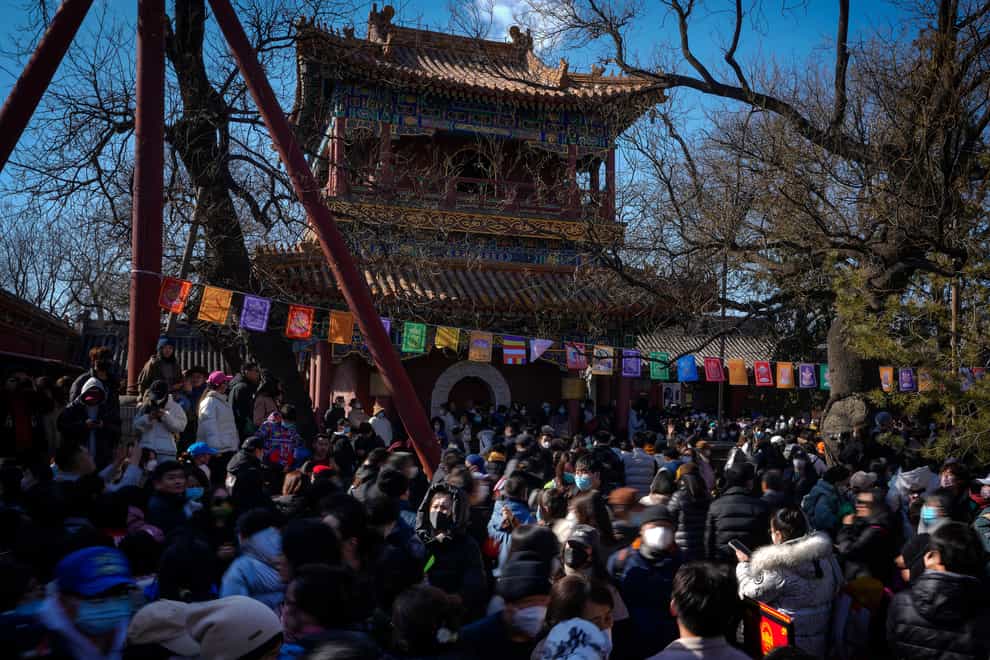 People wearing face masks visit the Yonghegong Lama Temple to watch a ritual ceremony for the Tibetan New Year in Beijing (Andy Wong/AP)