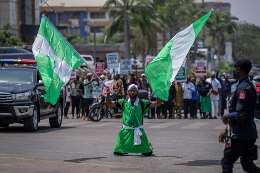 A demonstrator holds two Nigerian flags as he and others accusing the election commission of irregularities and disenfranchising voters make a protest in Abuja, Nigeria (Ben Curtis/AP)