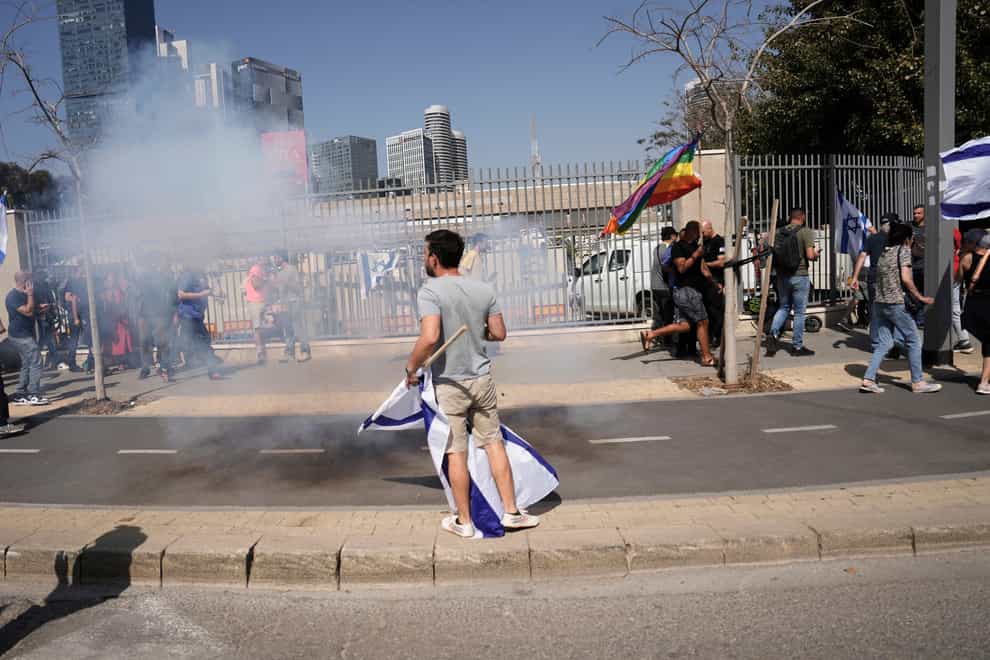Israelis react to stun grenades fired by police during a protest against plans by Prime Minister Benjamin Netanyahu’s new government to overhaul the judicial system (Oded Balilty/AP)