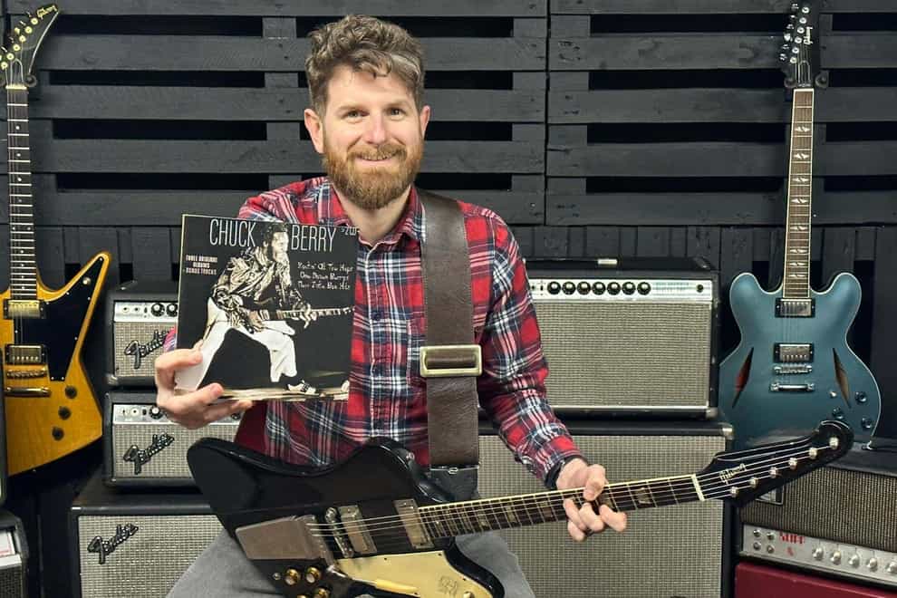 Auctioneer Luke Hobbs posing with Chuck Berry’s guitar (Gardiner Houlgate/PA)