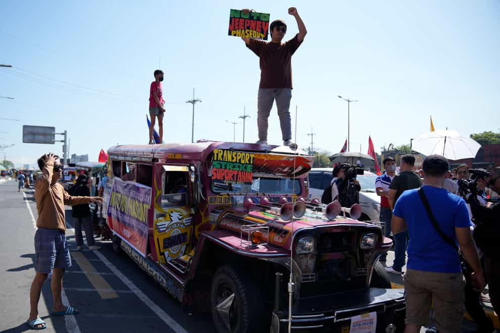 An activist holds a sign on top of a passenger jeepney (AP)