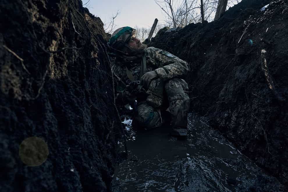 A Ukrainian soldier takes cover in a trench (AP)