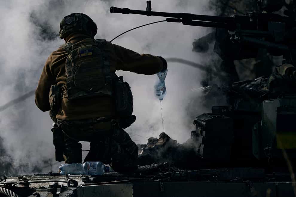 A Ukrainian serviceman puts out a fire on a burning tank in Chasiv Yar, Donetsk region, Ukraine (Libkos/AP)